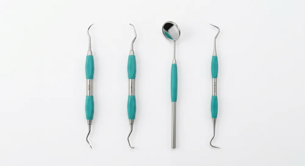 Dental cleaning instruments — mirror, scaler, curette, and explorer — arranged on a clean white surface